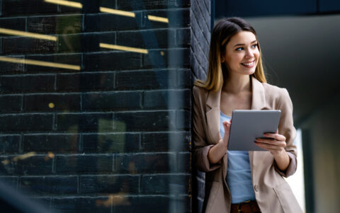 Portrait of a successful business woman using digital tablet in front of modern business building